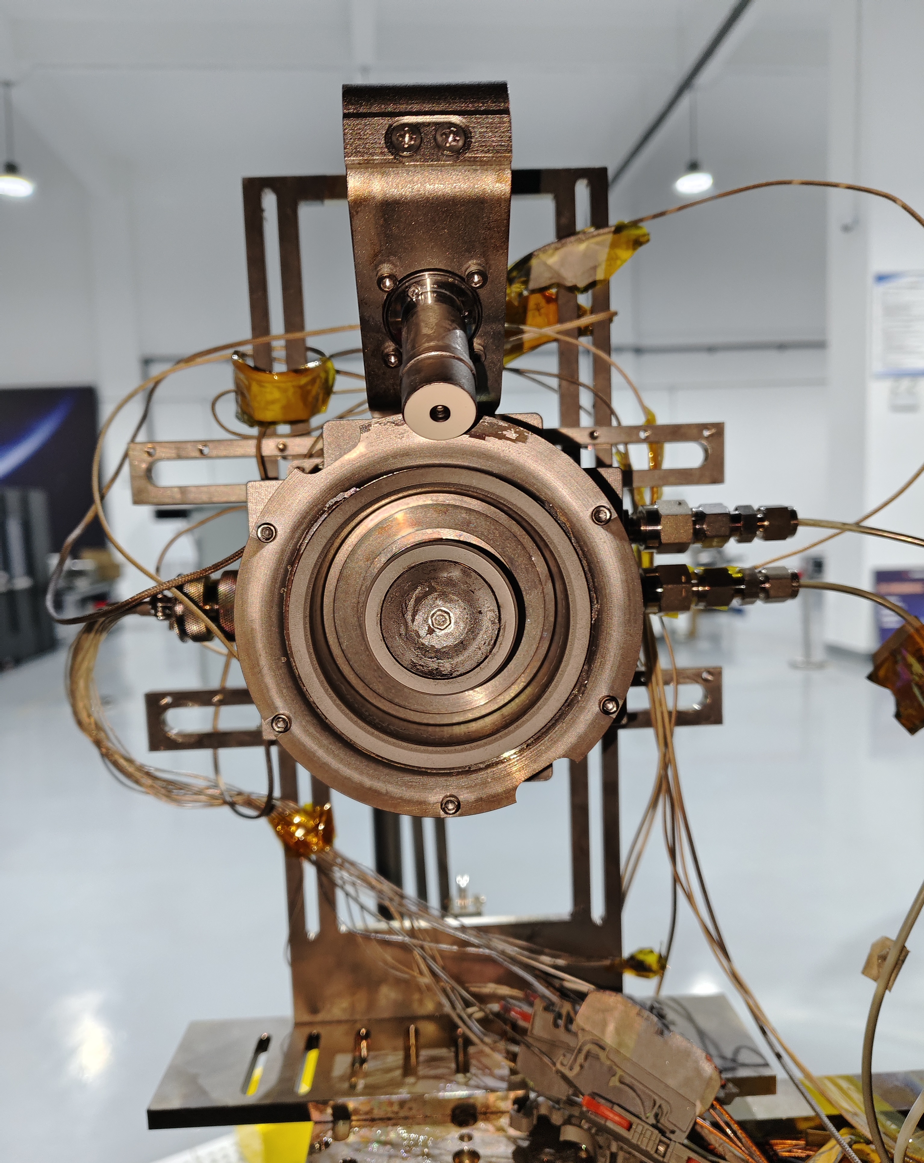 Hall thruster mounted on a laboratory test stand with wiring and feed lines